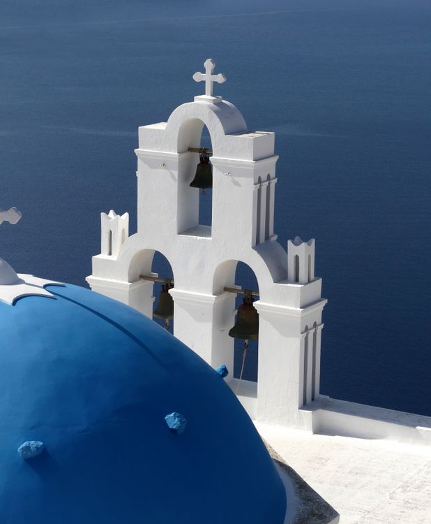 The Three Bells of Fira church in Firostefani with blue domes against the caldera backdrop