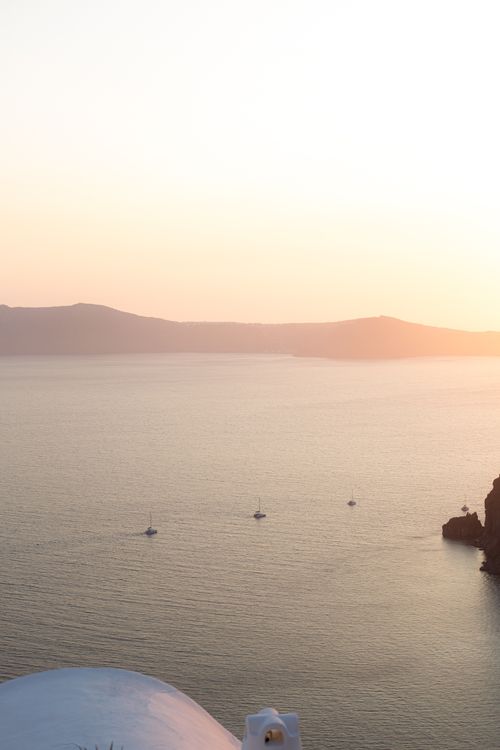 Golden sunset over the Santorini caldera with silhouetted cliffs and the Aegean Sea